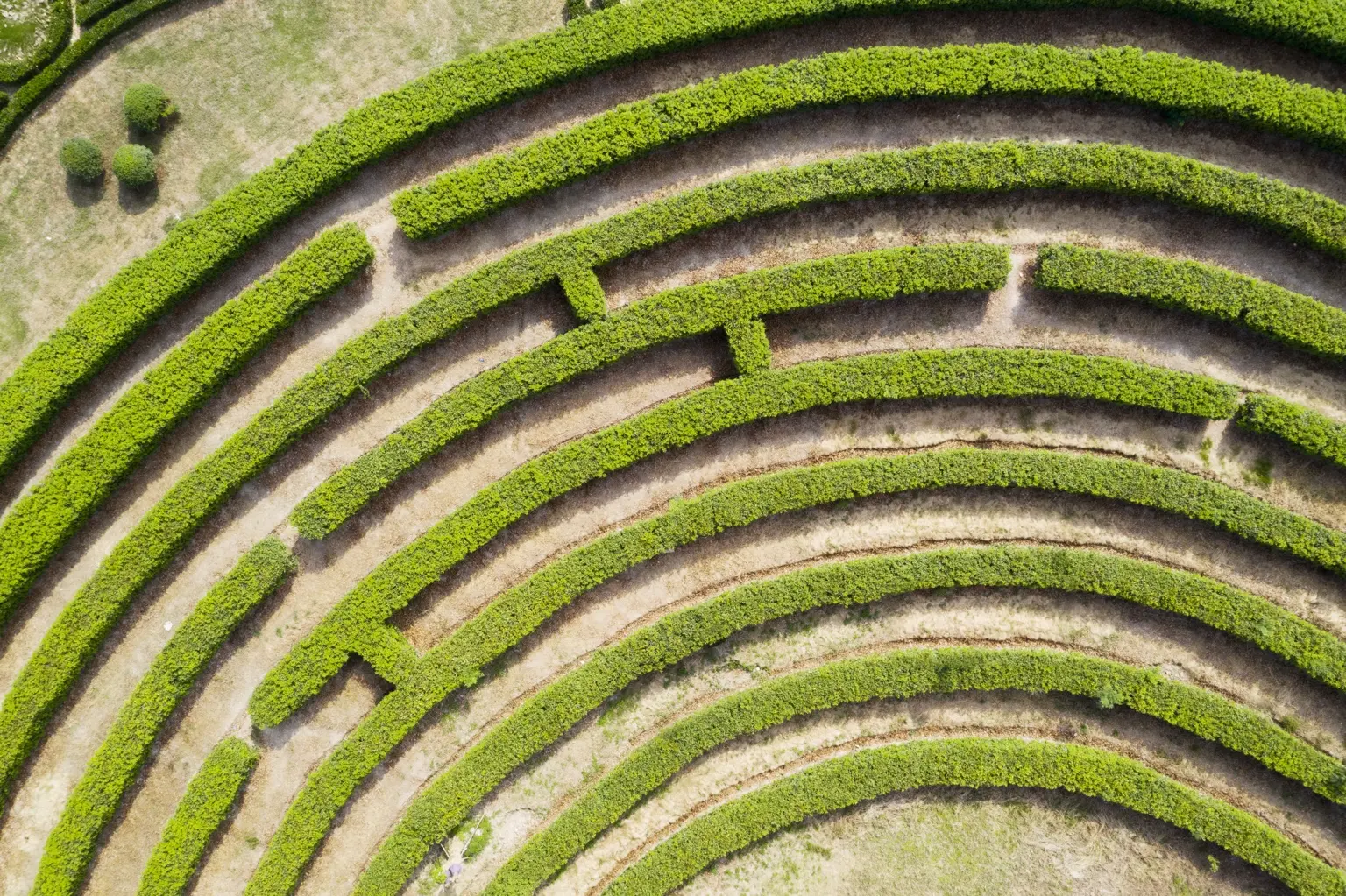 Luftaufnahme eines grünen Heckenlabyrinths mit verschlungenen Wegen als Sinnbild für Planung und Orientierung im Businessplan.