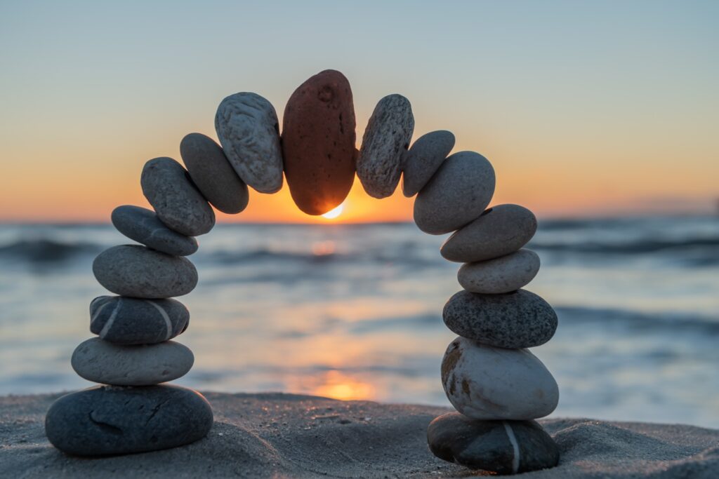 Steinbogen am Strand bei Sonnenuntergang als Symbol für das Zusammenspiel von Hauptjob, Familie und Selbstständigkeit