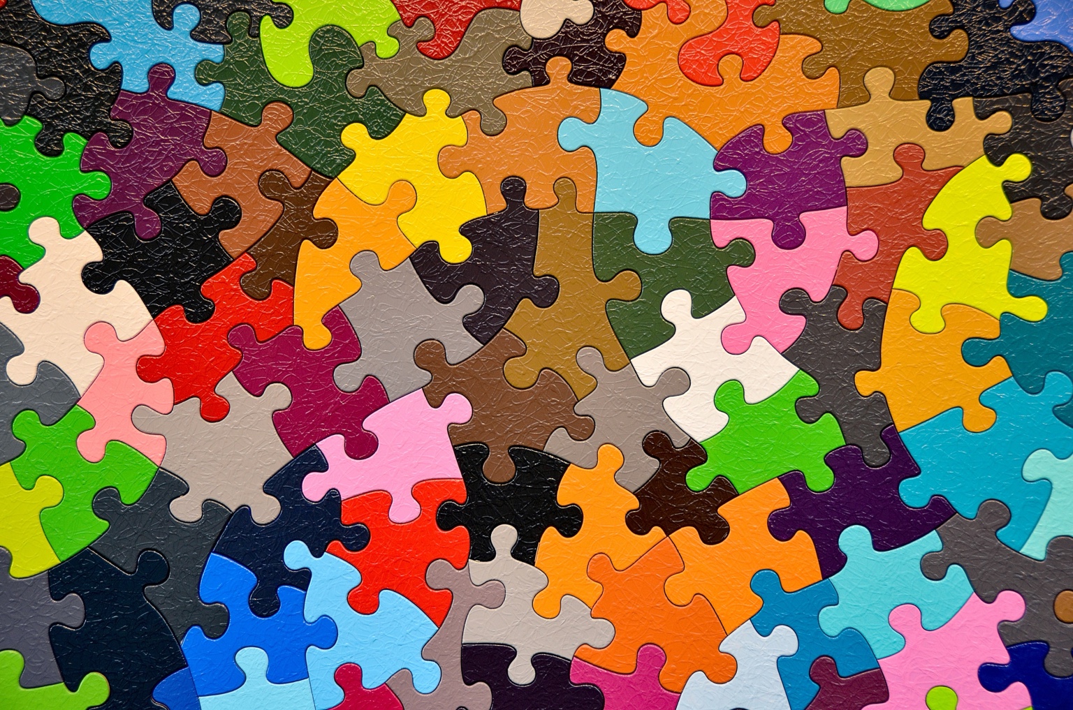 Nahaufnahme ineinandergreifender Puzzleteile in unterschiedlichen Farben.